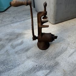 antique cast-iron manual meat grinder with a wooden handle and tabletop clamp  