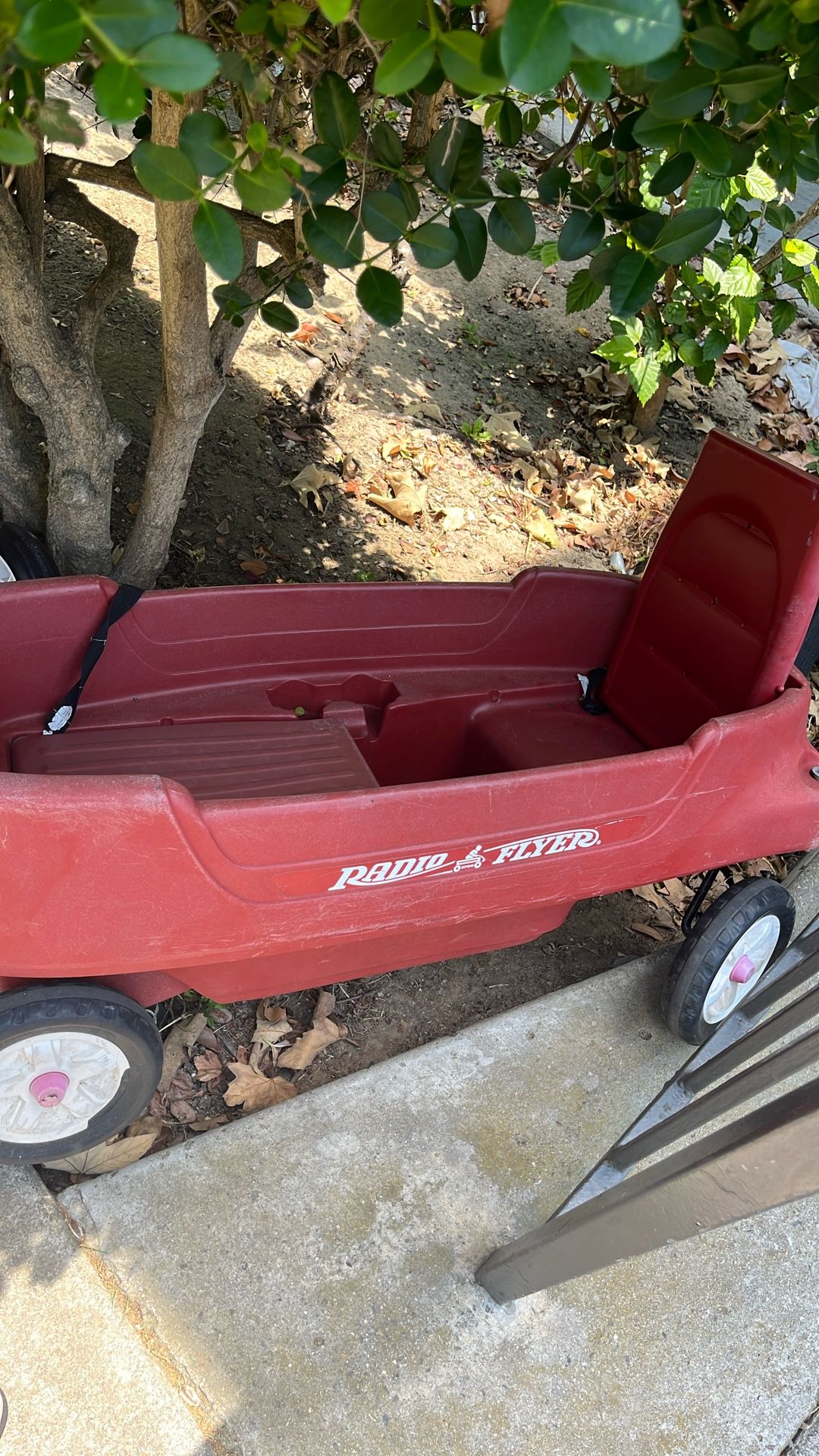 A large red stroller that is also used to transport things. It has two seats that can accommodate two children.