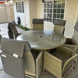 Ballero 5 Ft Diameter round outdoor dining set featuring a hand-woven synthetic wicker table with a tempered glass top and Seven Reclining Armchairs
