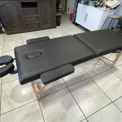 massage table with a black finish and wooden legs. 
