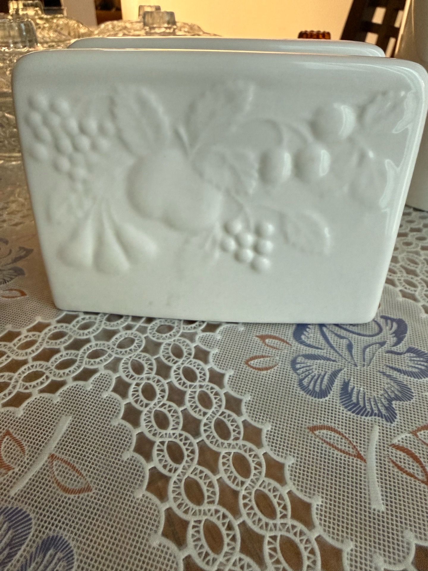 1 white ceramic napkin holder featuring an embossed fruit and grape pattern.