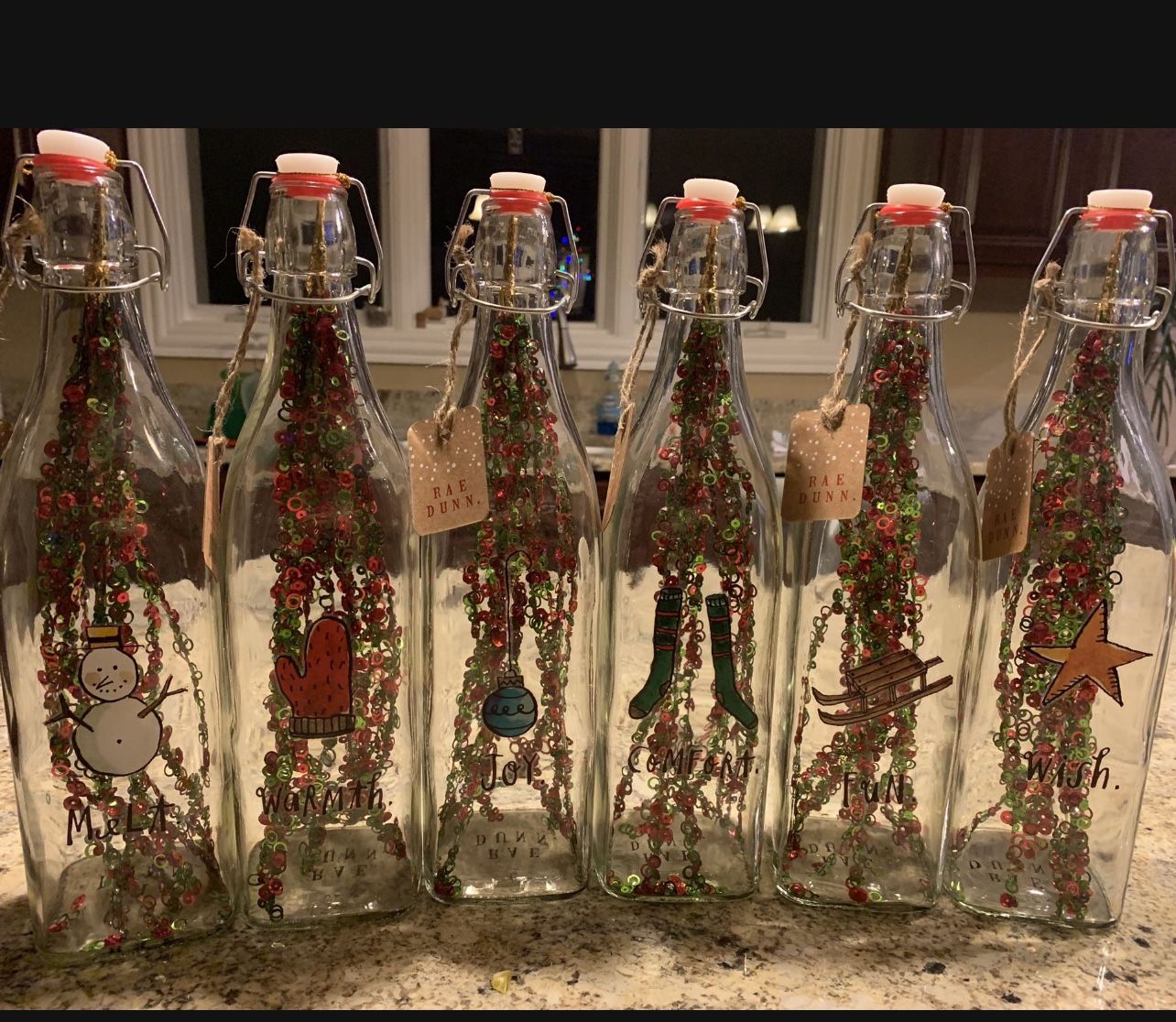 RAE DUNN GLASS BOTTLES WITH WINTER LOGOS. Added inside is a Christmas Ornament. Complete set of 6! SEE PHOTOS AMAZING CHRISTMAS DECORATION!!🎅🏽