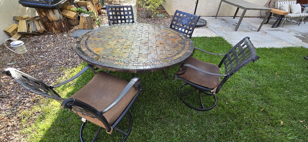 Stone patio table with 4 swivel and rocking chairs.