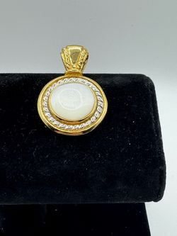 A round two -tone pendant featuring an iridescent white mother -of /pearl center stone