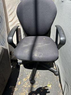 Small black fabric office chair with armrests and wheels
