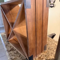 This is a small, freestanding wooden wine rack designed for a countertop or table