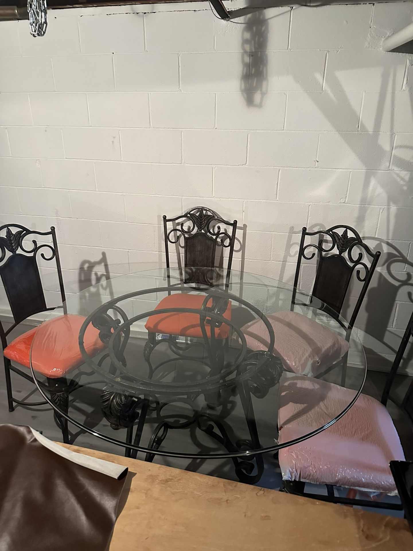 Beautiful Wrought Iron  & round glass dining table with 4 orange newly upholstered seats.
