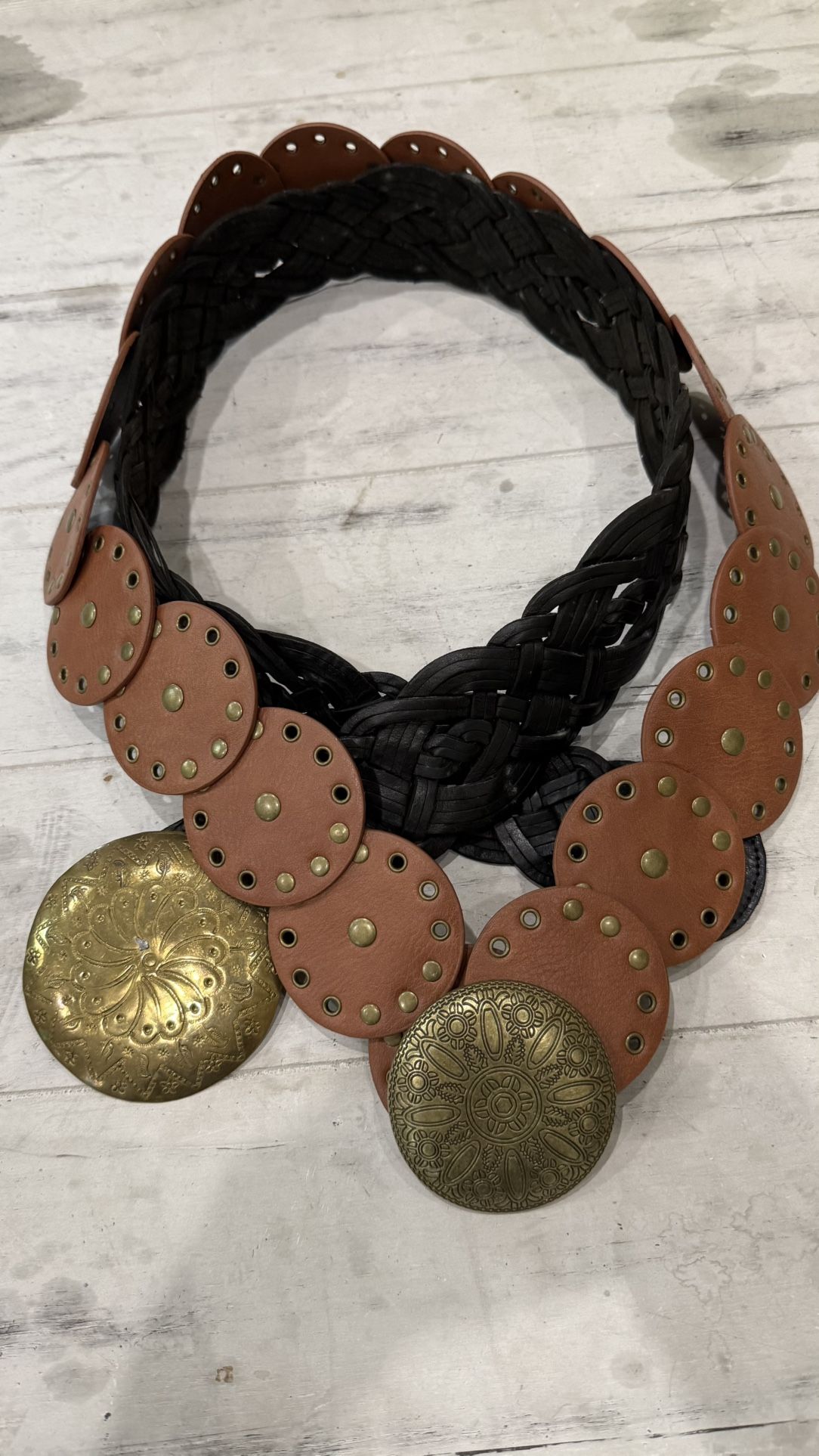 A pair of boho-style belts featuring oversized antique-gold medallions and circular leather accents.