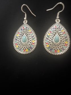 Vibrant teardrop-shaped earrings with a silver-tone metal finish. These earrings have a filigree-style design with multi-colored enamel accents in red