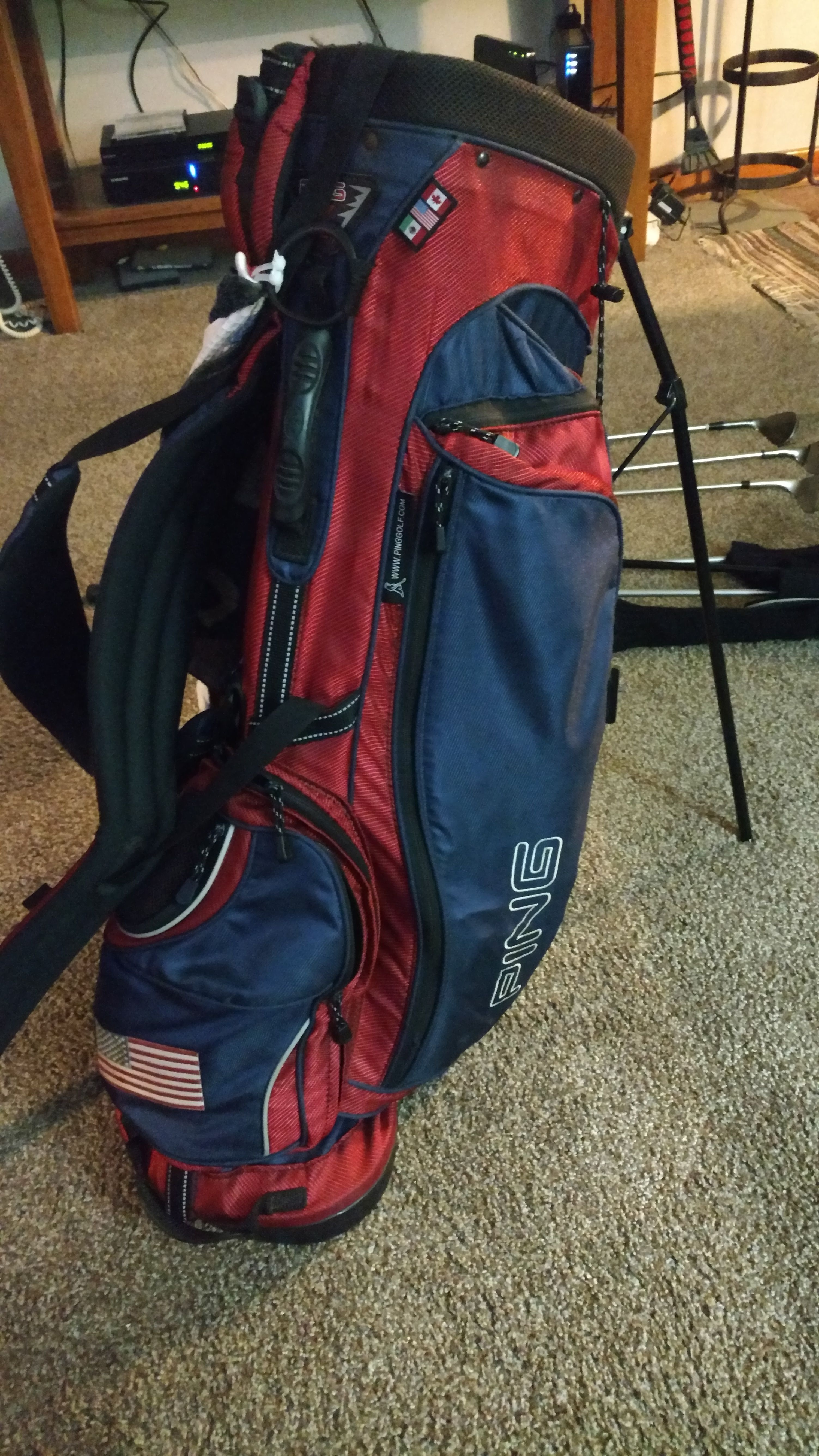 Ping golf bag w brookside country club logo on the other side and an American flag on the bottom where the ball bag is