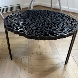 Black Kartell T-Table with an intricate lace-like cutout top