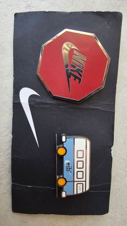 Nike collectible lapel pins, featuring an enamel octagonal stop sign with the Swoosh logo and a vintage-style bus design.The set includes two unique p