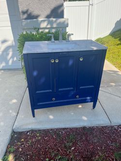 freestanding bathroom vanity cabinet with a marble countertop and sink