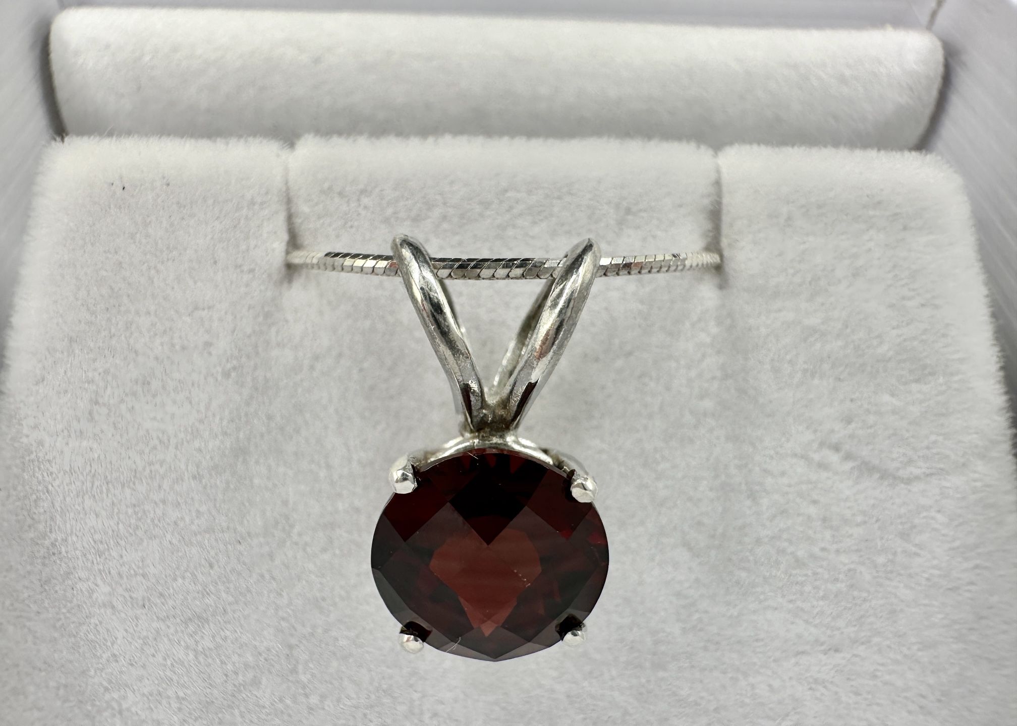 round 7mm garnet set in a sterling silver pendant with a sterling silver snake chain