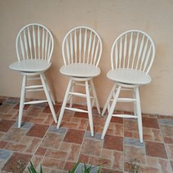 THREE SOLID WOOD COUNTER HEIGHT SWIVEL BAR STOOLS.