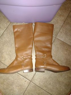 Stylish Michael Kors knee-high boots. Boots have tan leather upper and rubber outsole. Features gold-tone buckle detail and MK logo on side. Size 11M