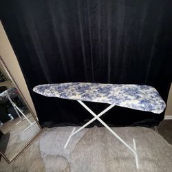 adjustable-height ironing board with a blue and white floral-patterned cover. 