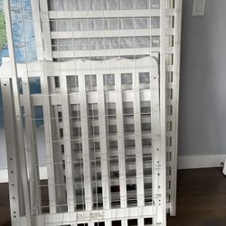 White baby crib with a mattress