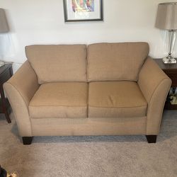 Khaki colored fabric loveseat. Seats 2