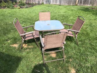 Glass top table with four matching chairs, perfect for garden or patio.