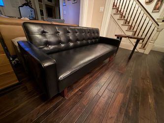 Mid-century modern convertible futon sofa bed upholstered in black faux leather