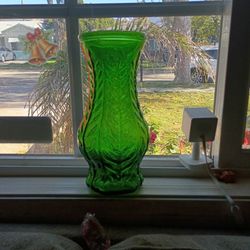 This is a vintage FTD emerald green glass vase with an embossed fern or leaf design. 