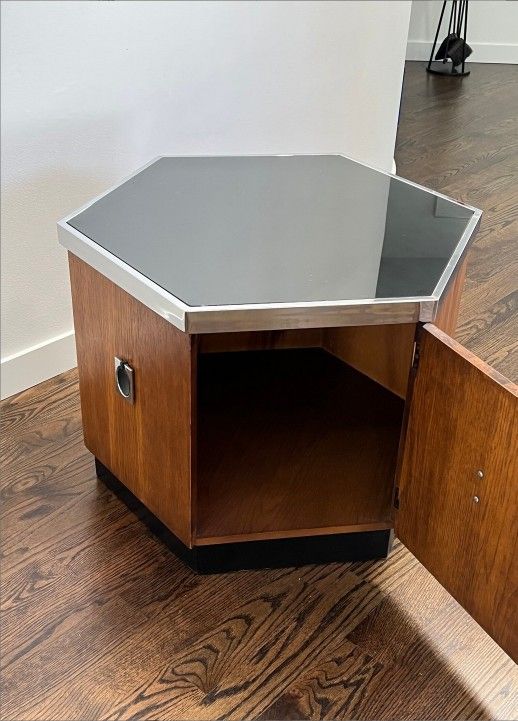 Mid Century Hexagonal Chrome Accent Side Table/ Cabinet. It consist of smoked glass top with chrome trim and hinged door, it rests on a plinth base. I