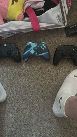 Two Xbox 360 controllers and another controller that is stills series