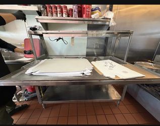 stainless steel kitchen prep table, a common fixture in commercial food service environments for food preparation or assembly