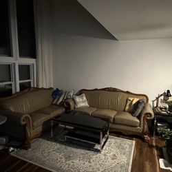 2 Beautiful, beige leather Couches with carved wooden accents.