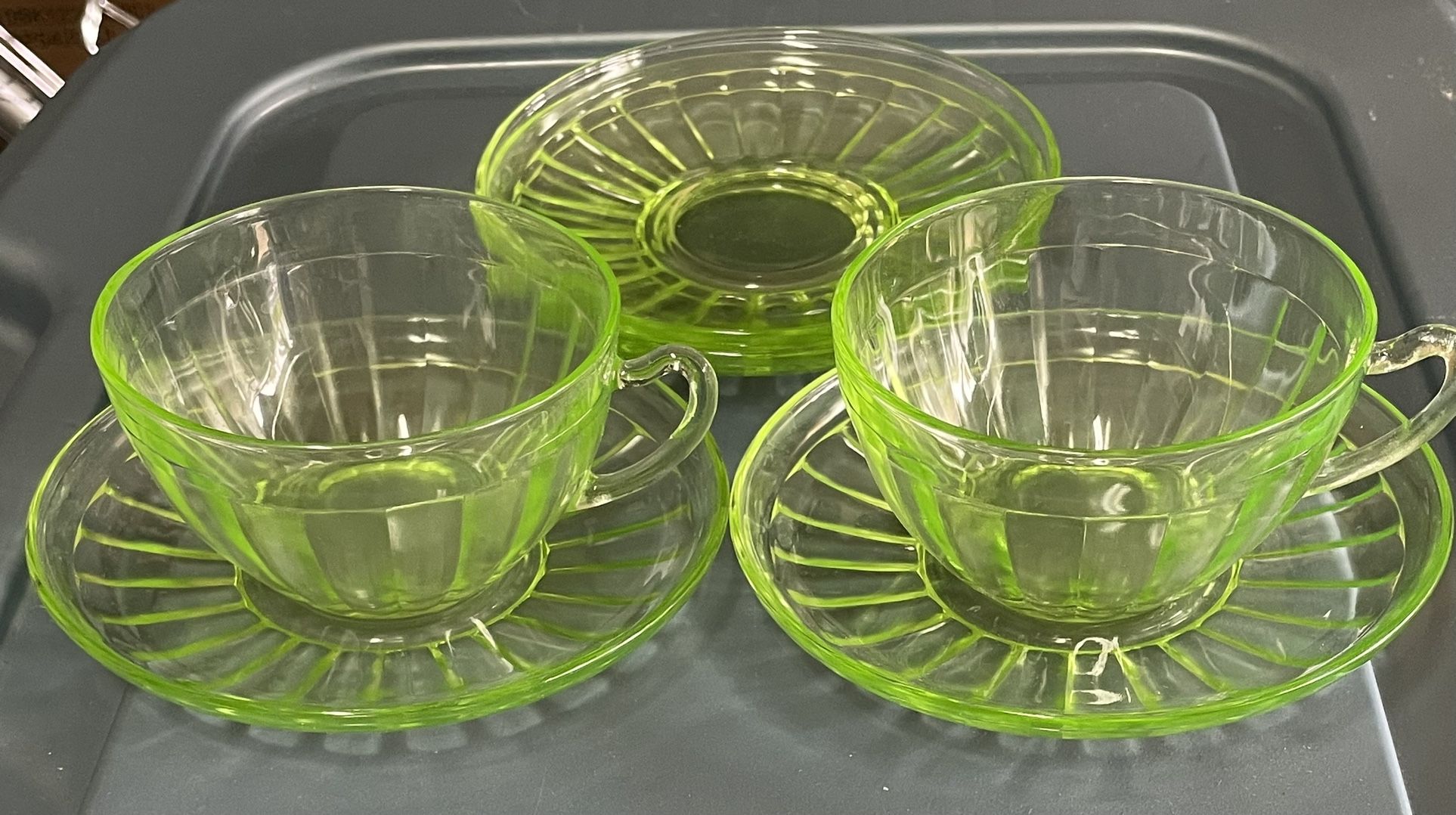 4 green depression glass saucers and 2 matching tea cups