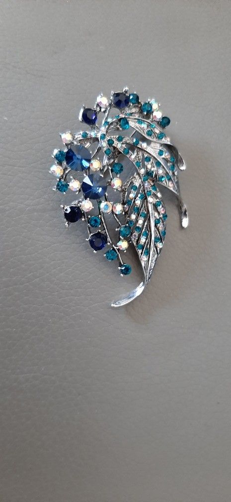 Silver tone brooch with green and blue stones.
