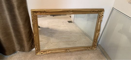 Large, ornate Baroque-style wall mirror featuring an antique gold finish and detailed floral scrollwork along the wooden frame. Measures 41” wide by 2