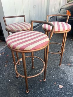 Pair of mid century low brass barstools with pink cabana stripe