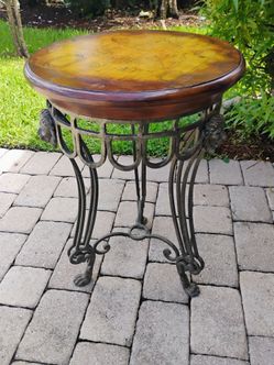 Vintage style round accent table with antique world map on top and ornate case metal legs adorned with sculpted lion heads tapering down to claw feet.
