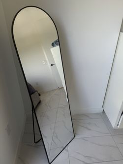 modern black arched full-length mirror with a stand