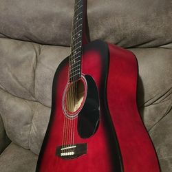 Vibrant red sunburst acoustic guitar from Lauren. This instrument has a wooden body with a black pickguard and chrome tuning pegs. It is a full-sized 