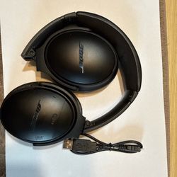 Black Bose QuietComfort 35 wireless over-ear headphones have a foldable design with cushioned ear cups and an adjustable headband. A micro-USB chargin