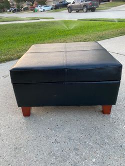 Square storage ottoman in black leather-look finish.