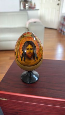 hand-painted enameled Russian Orthodox wooden icon egg featuring a traditional depiction of Jesus Christ on a matching black pedestal stand