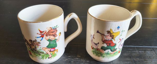 vintage mid-century ceramic child's mug with a crackled glaze finish, gold-trimmed rim, and colorful illustrations of playing children and animals