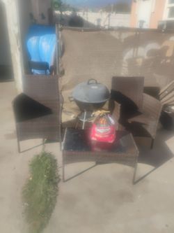 Two chairs one grill one small table a little bit of charcoal and a speaker