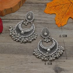 Vintage and distressed red exotic Bohemian style earrings with tassels and diamonds, featuring an exaggerated and unique look.