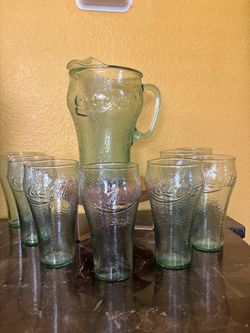 A vintage Coca Cola pitcher with 8 green glasses
