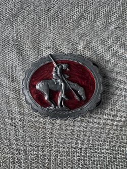 vintage 1980s "End of the Trail" belt buckle featuring a pewter Native American figure on horseback against a red enameled background