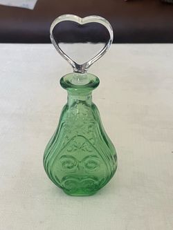 Green glass perfume bottle with embossed scrollwork and a heart-shaped stopper.