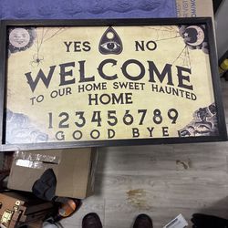 Ouija board-themed decorative sign or mat suitable for Halloween home decor.     Design: Features the classic Ouija board layout with "YES", "NO", "GO