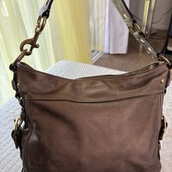 Metallic gold leather Coach shoulder bag with gold hardware, featuring a spacious interior and multiple pockets