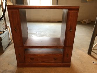Wooden TV stand with drawers on sides and bottom drawer.