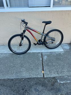 El objeto seleccionado es una bicicleta infantil Specialized Hotrock 24 de color gris con detalles rojos y amarillos.